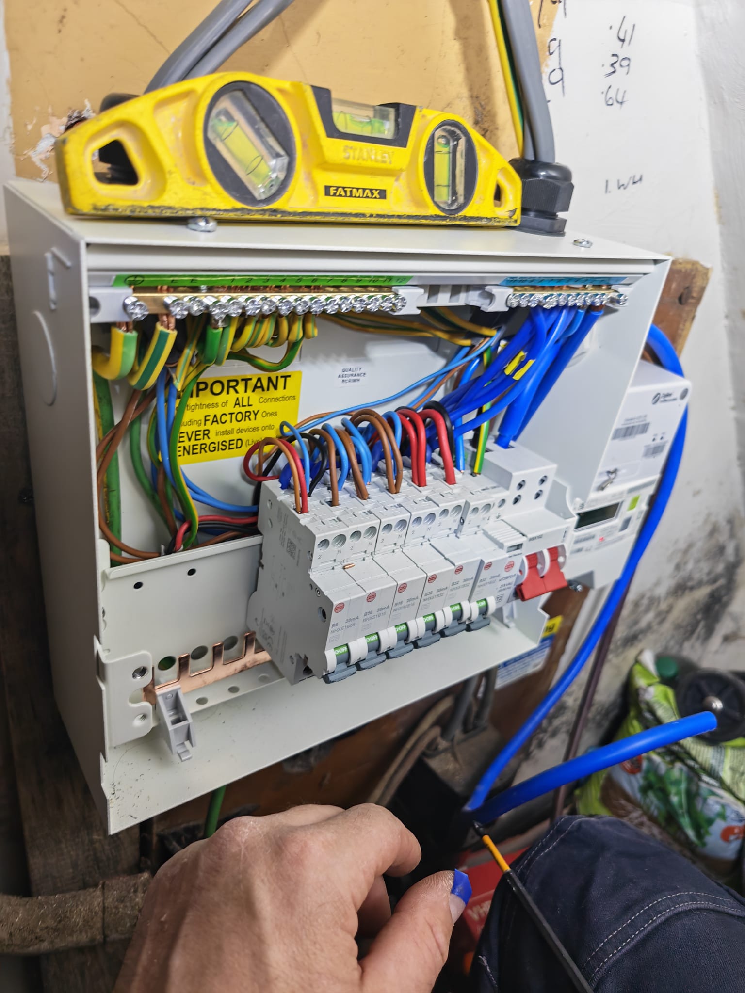 Electrician's hand working on newly wired consumer unit circuits