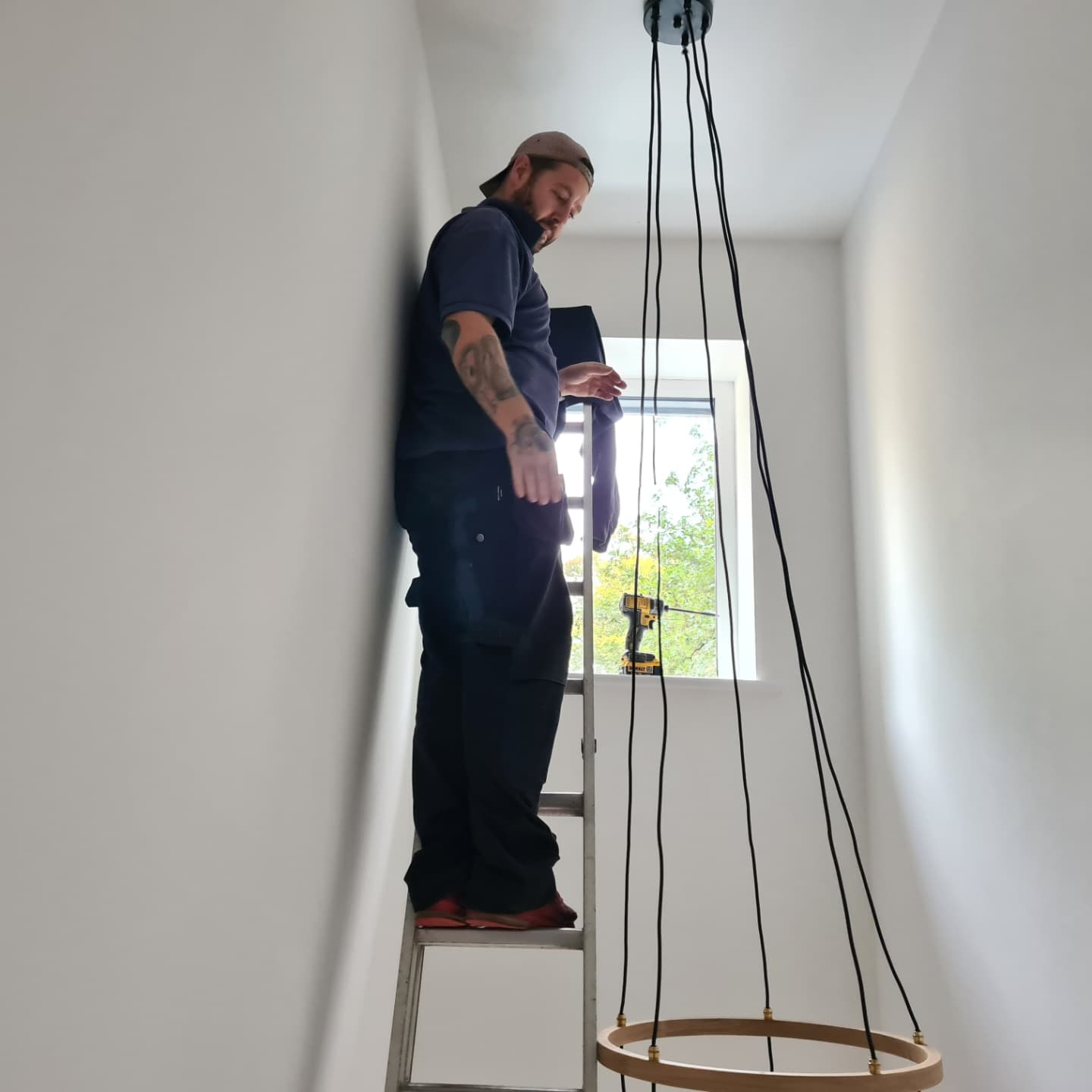Electrician on ladder — chandelier install in progress